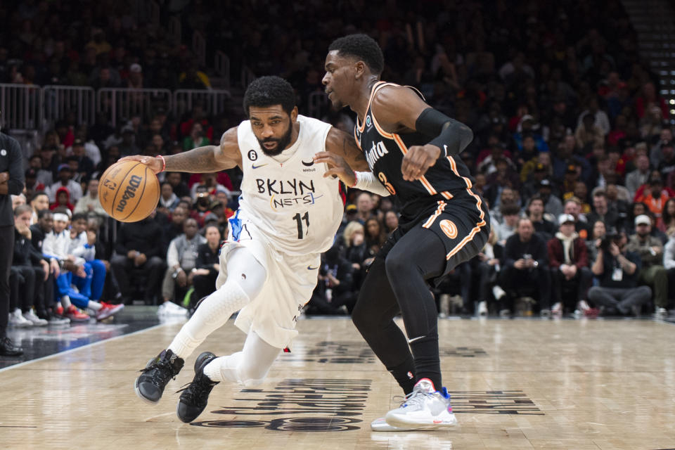 Brooklyn Nets guard Kyrie Irving (11) drives to the basket against Atlanta Hawks guard Aaron Holiday during the second half of an NBA basketball game, Wednesday, Dec. 28, 2022, in Atlanta. (AP Photo/Hakim Wright Sr.)