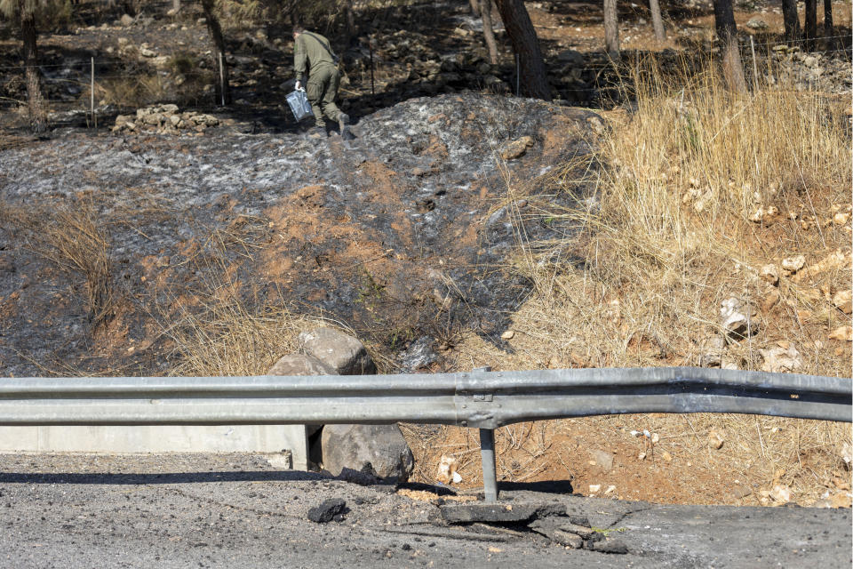 Israeli soldiers search for remains of a rocket near the village of Avivim on the Israel-Lebanon border, Monday, Sept. 2, 2019. Hezbollah militants on Sunday fired a barrage of anti-tank missiles into Israel, prompting a reprisal of heavy Israeli artillery fire in a rare burst of fighting between the bitter enemies. (AP Photo/Ariel Schalit)