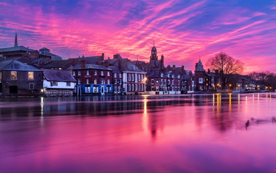The sky glows pink over the River Ouse in York on Tuesday morning where water levels rose to 3.67m during Storm Isha, breaking their banks and flooding the city centre