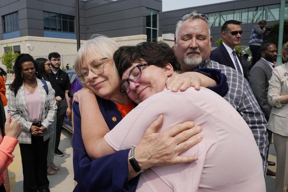 Karen Kobylik, foreground is hugged after Michigan Gov. Gretchen Whitmer signed legislation, Monday, May 22, 2023, in Royal Oak, Mich., to create extreme risk protection orders, which authorize family, police officers, or medical professionals to seek a court order to temporarily keep guns out of the hands of someone who represents a danger to themselves or others. Karen's daughter Ruby Taverner shot and killed her boyfriend and her brother Bishop Taverner before taking her own life hours later on May 8, 2022. (AP Photo/Carlos Osorio)
