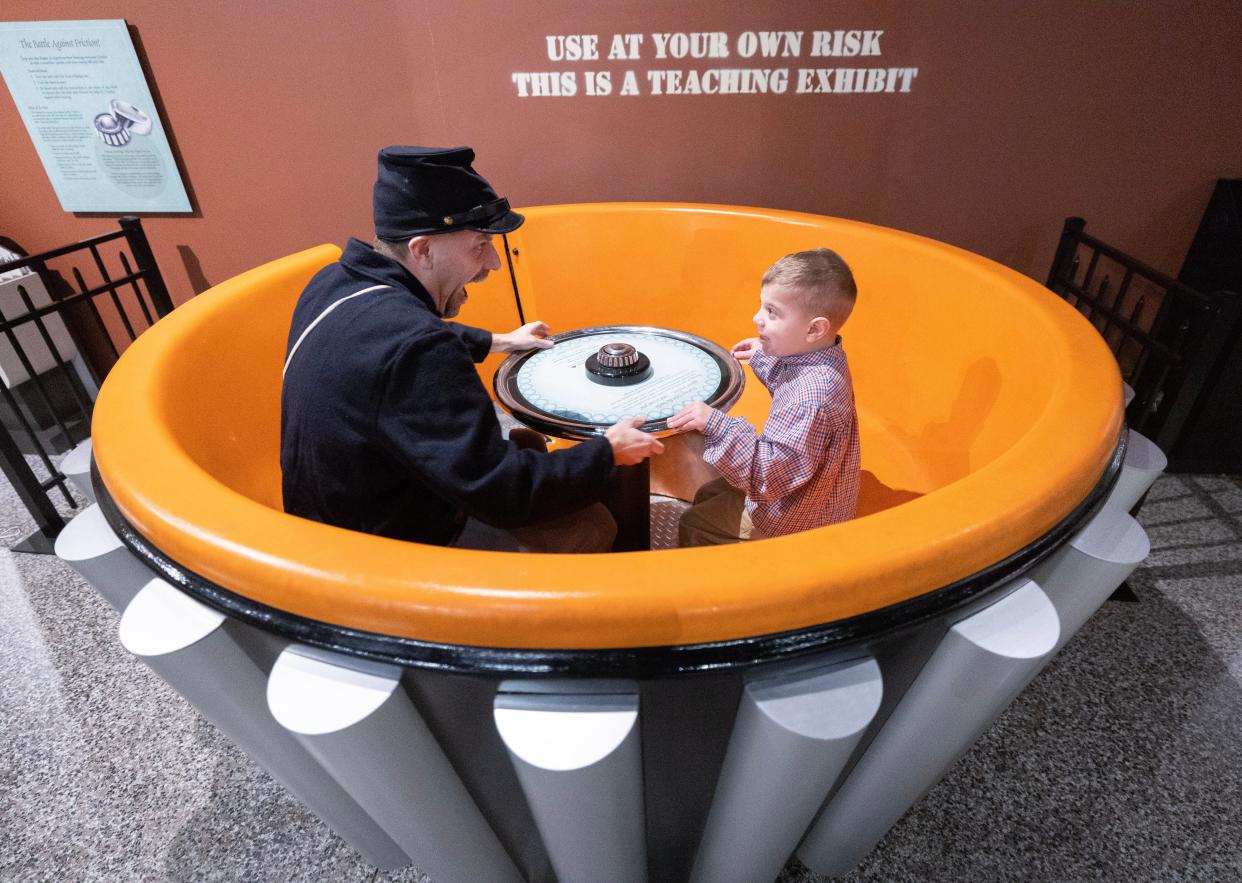 Dennis Klingensmith and his son Silas, 6, take a spin on a giant-sized Timken roller bearing at the McKinley Presidential Library & Museum in Canton.