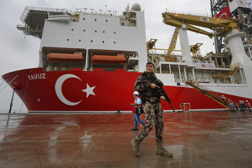 A Turkish police officer patrols the dock, backdropped by the drilling ship 'Yavuz' scheduled to be dispatched to the Mediterranean, at the port of Dilovasi, outside Istanbul, Thursday, June 20, 2019. Turkish officials say the drillship Yavuz will be dispatched to an area off Cyprus to drill for gas. Another drillship, the Fatih, is now drilling off Cyprus' west coast at a distance of approximately 40 miles in waters where the east Mediterranean island nation has exclusive economic rights. The Cyprus government says Turkey's actions contravene international law and violate Cypriot sovereign rights. (AP Photo/Lefteris Pitarakis)