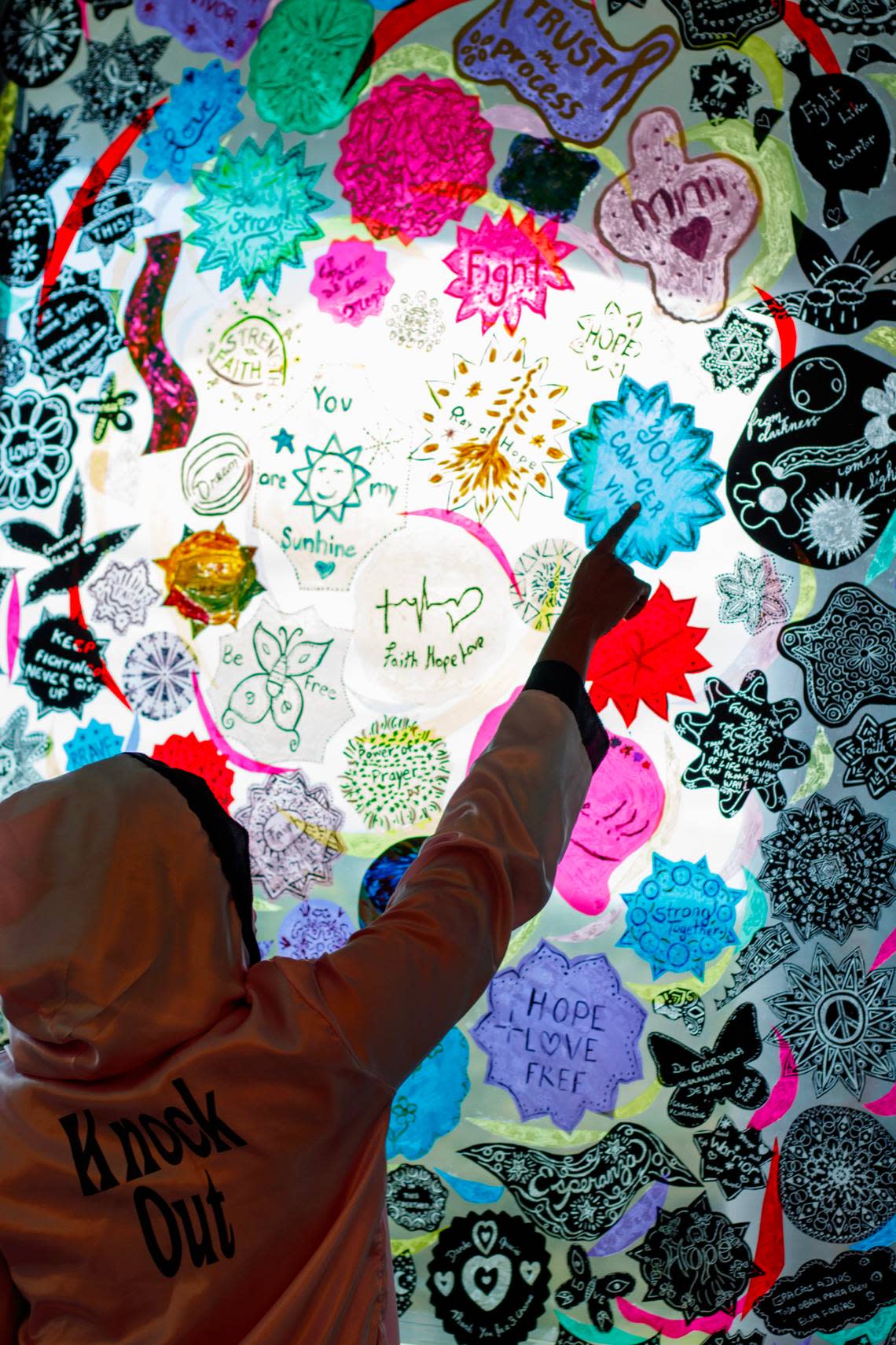 The Miami Cancer Institute has a window covered with artwork created by cancer patients. Breast cancer survivor Latoya Simmons, 42, while wearing the pink boxer robe that served as her armor during her chemotherapy, points to one of the pieces she made while undergoing treatment.