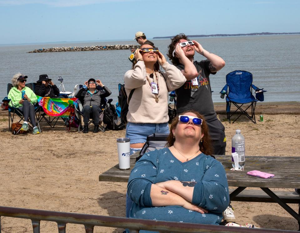 MCCC Agora reporters Destiny Gallina, left, and Mick Valentino, along with assistant editor Ashley Atkins, front, use protective glasses to view the emerging eclipse Monday at East Harbor State Park in Ohio.