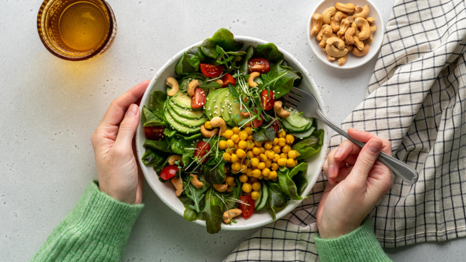 A woman's hands ready to eat a salad with legumes, nuts, and vegetables, which reduces the itch of hemorroids