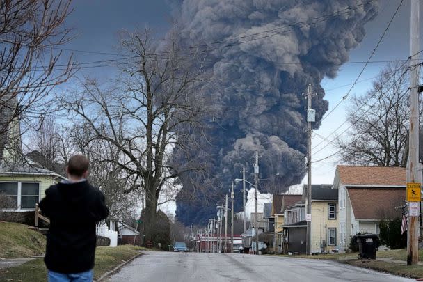 PHOTO: A man takes photos as a black plume rises over East Palestine, Ohio, during a controlled detonation of a portion of the derailed Norfolk Southern train, Feb. 6, 2023. (Gene J. Puskar/AP)