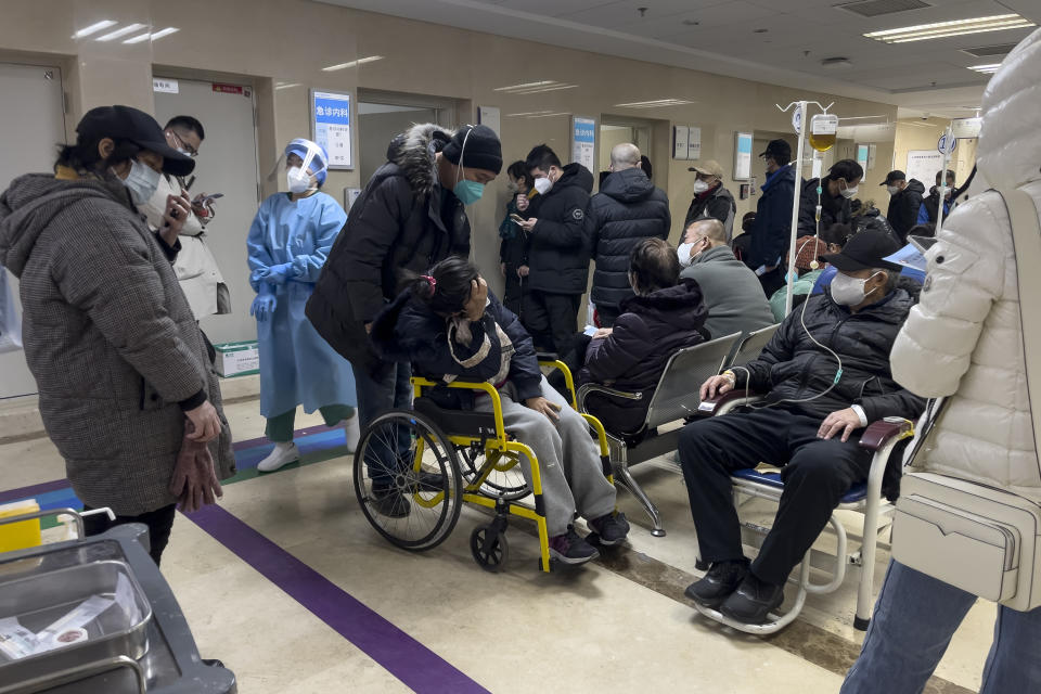A man pushes his relative in pain on a wheelchair as patients receive intravenous drips in the emergency ward of a hospital in Beijing, Thursday, Jan. 5, 2023. Patients, most of them elderly, are lying on stretchers in hallways and taking oxygen while sitting in wheelchairs as COVID-19 surges in China's capital Beijing. (AP Photo/Andy Wong)