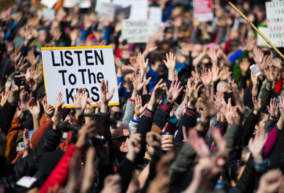 A rally with a sign raised that says "Listen to the kids"