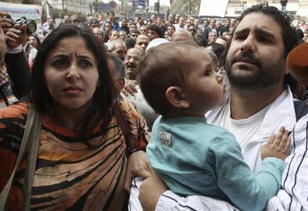 Alaa Abdel Fattah (R), one of the activists who was summoned by the public prosecutor on whether he had a role in the recent violent anti-Islamists protests, arrives with his wife and child to the public prosecutor's office in Cairo, March 26, 2013. REUTERS/Asmaa Waguih