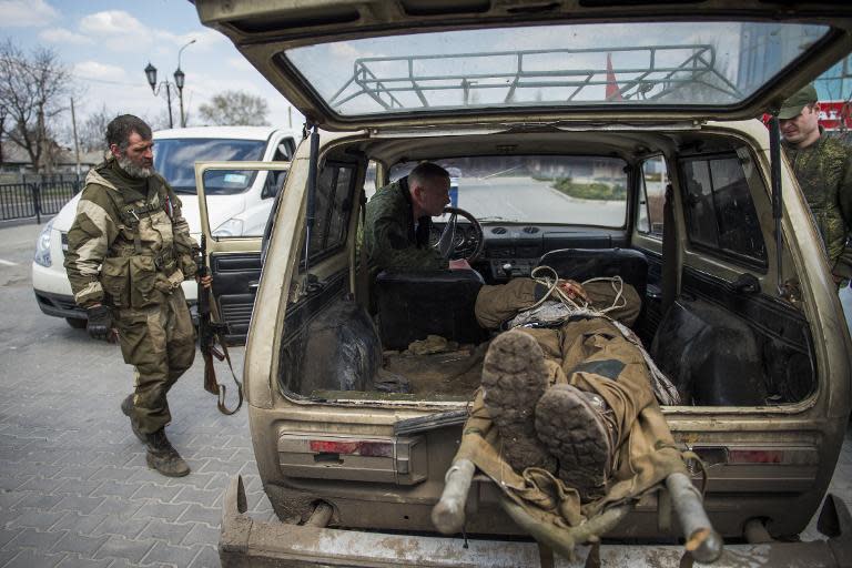 A separatist soldier looks at a body of a Ukrainian soldier killed during overnight fighting near Donetsk airport on April 13, 2015