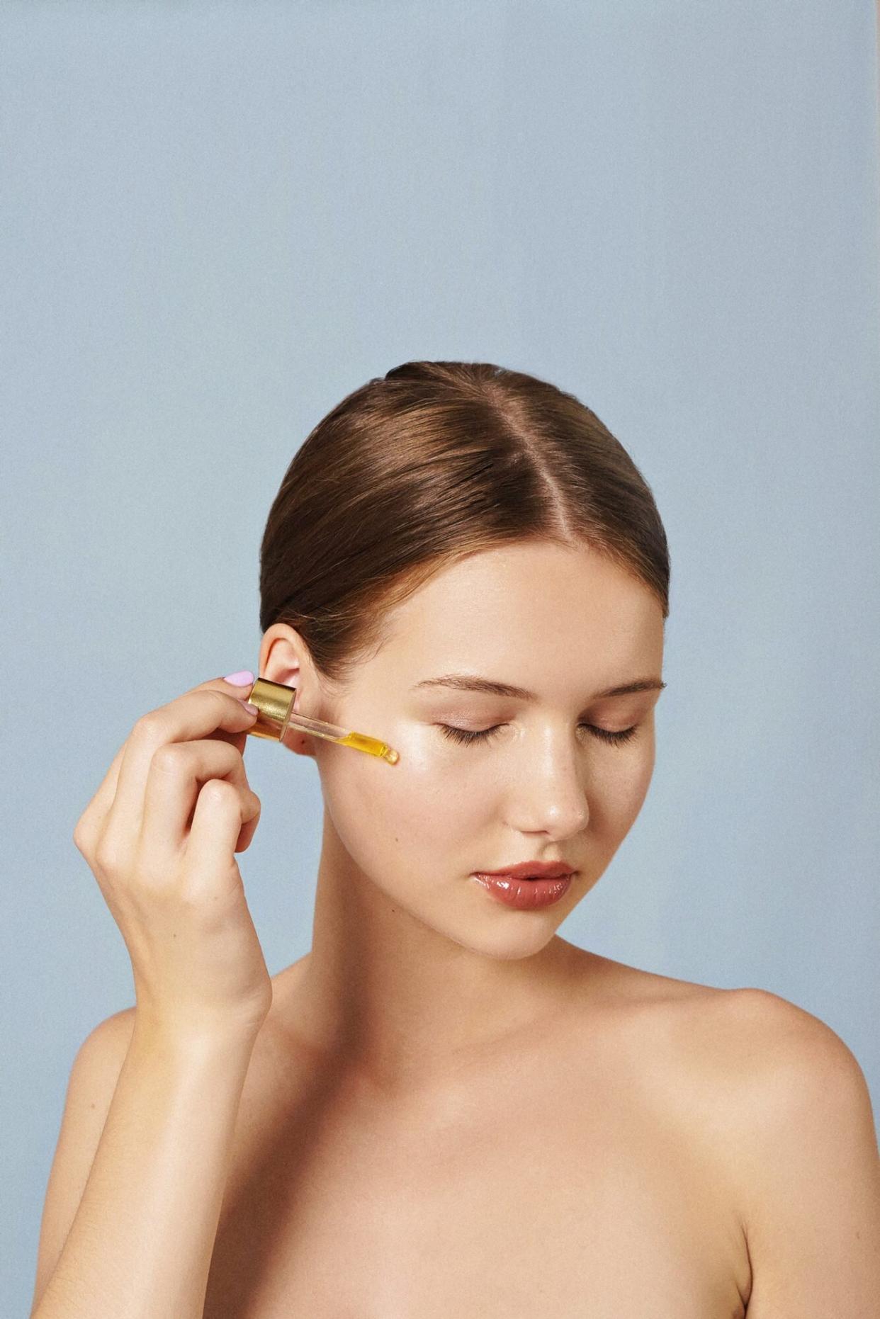 A woman applying serum to her skin