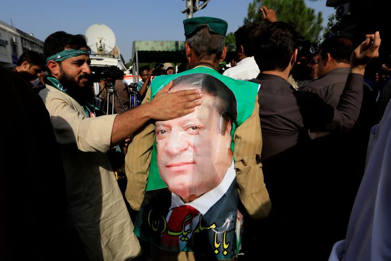 FILE PHOTO: A supporter of former Prime Minister Nawaz Sharif touches his picture as he celebrate with others following the court's decision in Islamabad, Pakistan