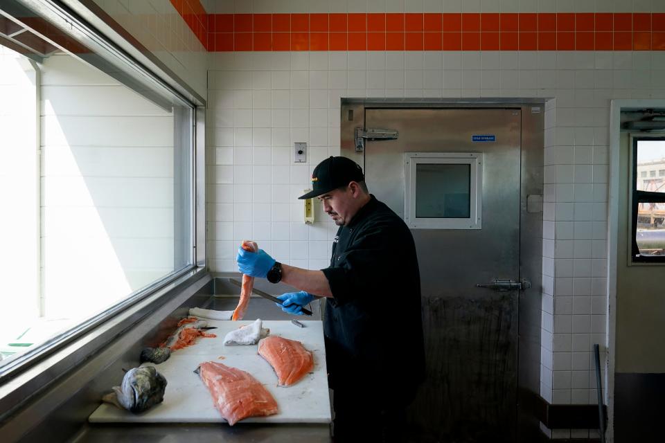 Luis Alvarenga, executive chef at Scoma's, cleans a farm-raised salmon in San Francisco on March 20. A federal regulatory group has voted to officially close king salmon fishing season along much of the West Coast after near-record low numbers of the fish, also known as chinook, returned to California's rivers in 2022.