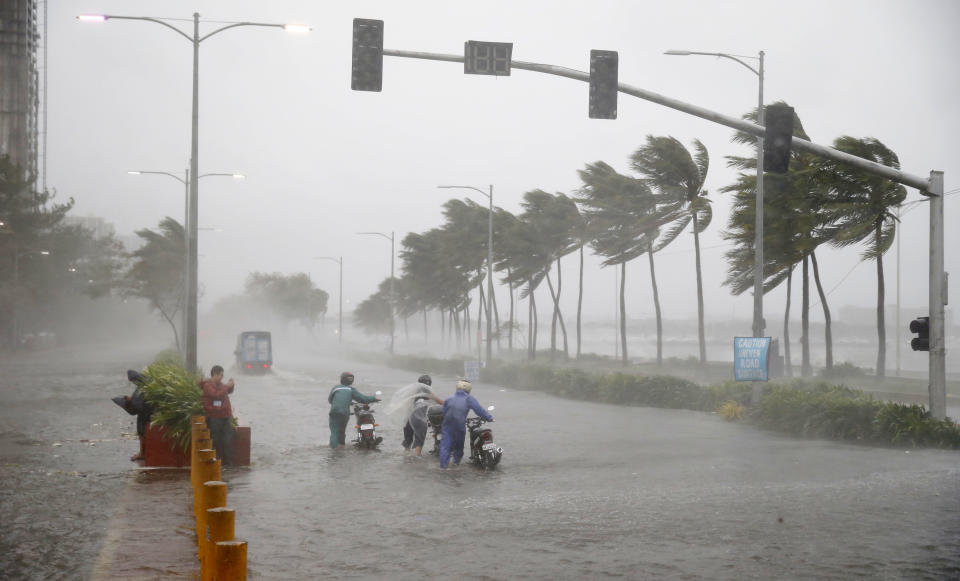 Motorists brave the rain and strong winds brought about by Typhoon Mangkhut which barreled into northeastern Philippines before dawn Saturday, Sept. 15, 2018 in Manila, Philippines. The typhoon slammed into the Philippines' northeastern coast early Saturday, its ferocious winds and blinding rain ripping off tin roof sheets and knocking out power, and plowed through the agricultural region at the start of the onslaught. (AP Photo/Bullit Marquez)