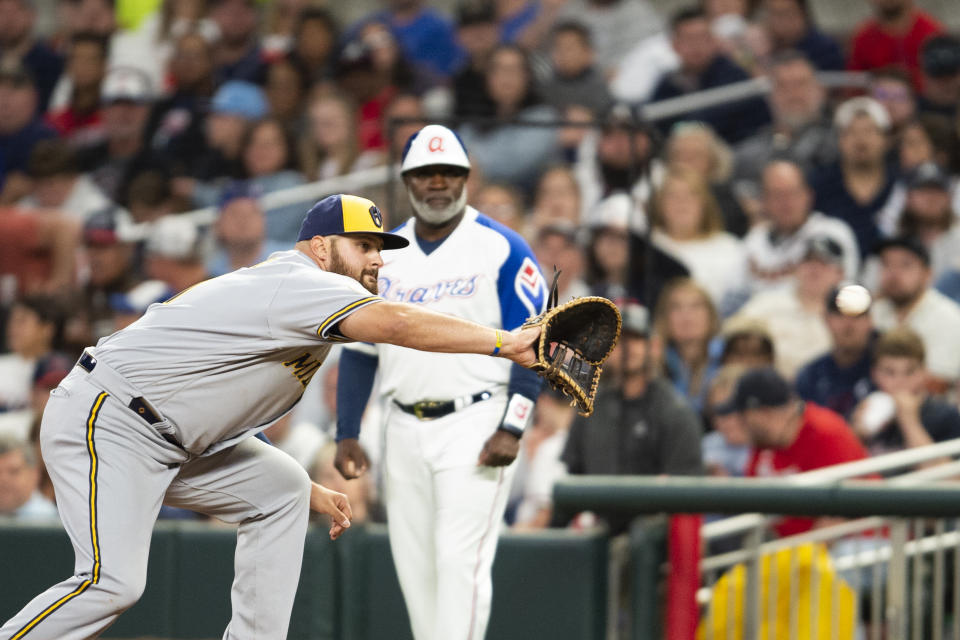 Milwaukee Brewers first baseman Rowdy Tellez, left, makes a catch during the sixth inning of a baseball game against the Atlanta Braves, Saturday, May 7, 2022, in Atlanta. (AP Photo/Hakim Wright Sr)