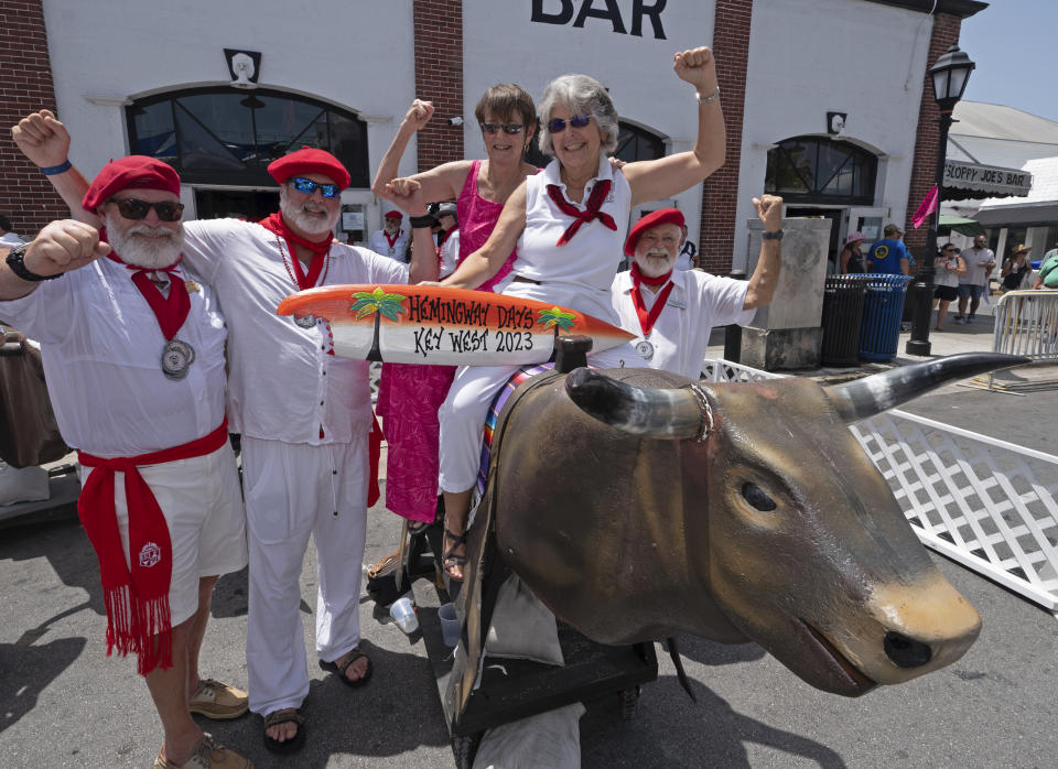 In this photo provided by the Florida Keys News Bureau, Ernest Hemingway look-alikes pose for photos with Hemingway Days festival attendees before the "Running of the Bulls" spoof Saturday, July 22, 2023, in Key West, Fla. The lighthearted take-off on the famed run in Pamplona, Spain, features replica bulls on wheels and is a focal element of the island city's annual Hemingway festival that ends Sunday, July 23. Hemingway lived and wrote in Key West throughout most of the 1930s. (Andy Newman/Florida Keys News Bureau via AP)