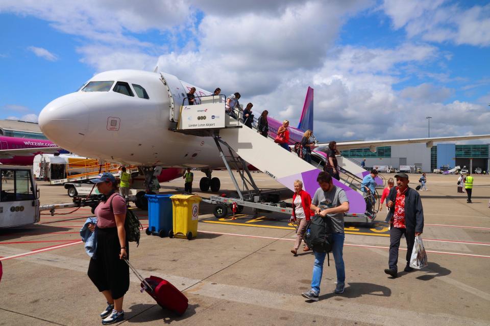 Airline LUTON, UK - JULY 12, 2019: Passengers disembark from the low-flying Wizz Air Airbus A320 aircraft at London Luton Airport in the UK. It is the fifth busiest airport in the UK