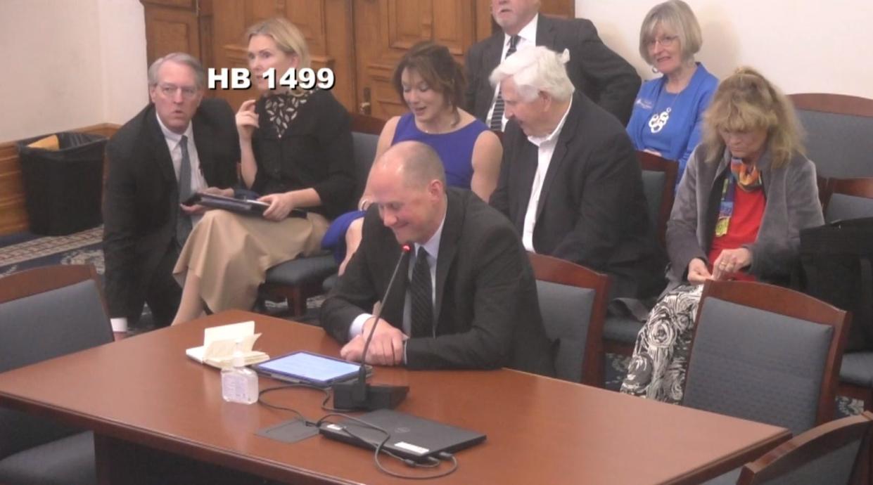 Mathew Norris, front, an attorney representing the city of Bloomington, and Monroe County Commissioner Penny Githens, in the back, in blue, smile after a state lawmaker suggests Monroe County and the city of Bloomington could "use a dad to tell them what to do" at the Senate Committee on Tax and Fiscal Policy, on April 11, 2023.