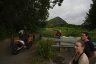 A couple watch bikers riding near Henin-Beaumont, northern France, Sunday, June 30, 2024. Several waves of industrial shutdowns have left unemployment levels above the national average, and 60% of the population earns so little it does not need to pay tax, according to data from France's national statistics agency.(AP Photo/Thibault Camus)