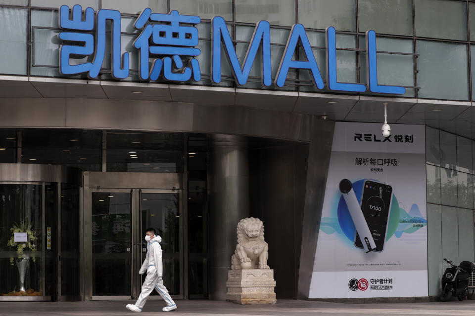 A worker wearing a protective suit to help curb the spread of the new coronavirus walks by a shuttered shopping mall following positive cases detected in Beijing, Tuesday, June 23, 2020. China reported close to two dozen new cases of coronavirus on Tuesday a day after a city government spokesperson said containment measures had slowed the momentum of an outbreak in the capital that has infected more than 200 people. (AP Photo/Andy Wong)