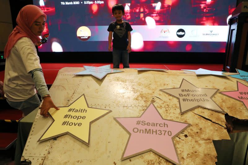 Victim's family member picks up a placard on debris of the missing Malaysia Airlines flight MH370 during its sixth annual remembrance event in Putrajaya