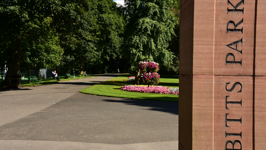 The entrance to Bitts Park with manicured lawns and flowers behind 