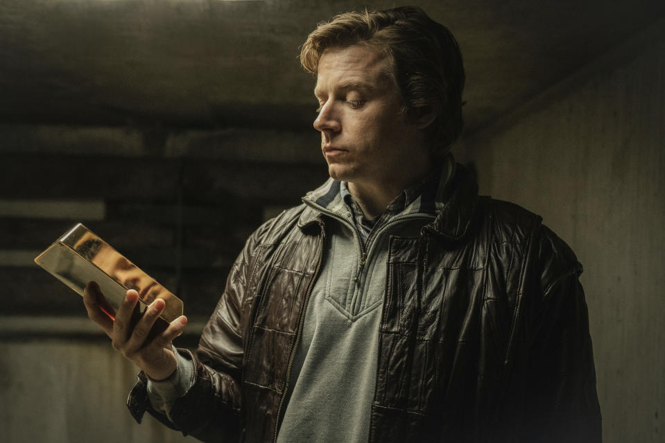 A man holds a gold bar in his hand.