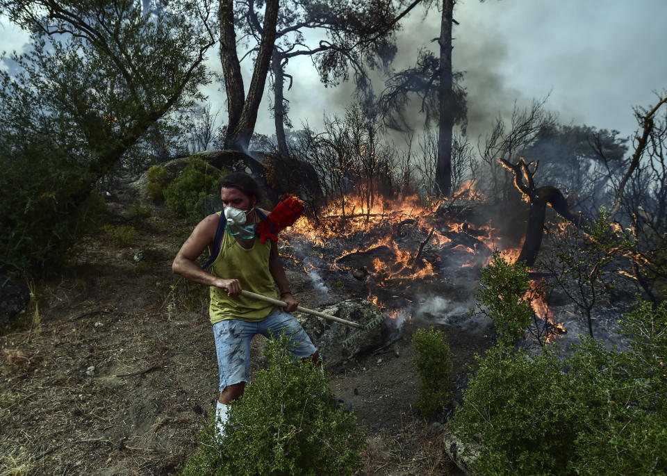 A volunteer works to extinguish a fire in Yatagan of the Mugla province, Turkey, Friday Aug. 6, 2021. Thousands of people fled wildfires burning out of control in Greece and Turkey on Friday, as a protracted heat wave turned forests into tinderboxes that threatened populated areas, electricity installations and historic sites. (Ismail Coskun/IHA via AP)