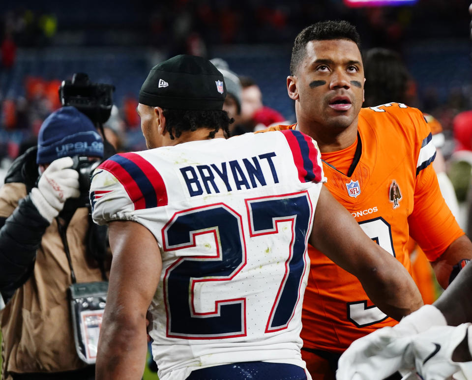 New England Patriots cornerback Myles Bryant, left, greets Denver Broncos quarterback Russell Wilson after an NFL football game at Empower Field at Mile High, Sunday, Dec. 24, 2023, in Denver. (AP Photo/Geneva Heffernan)