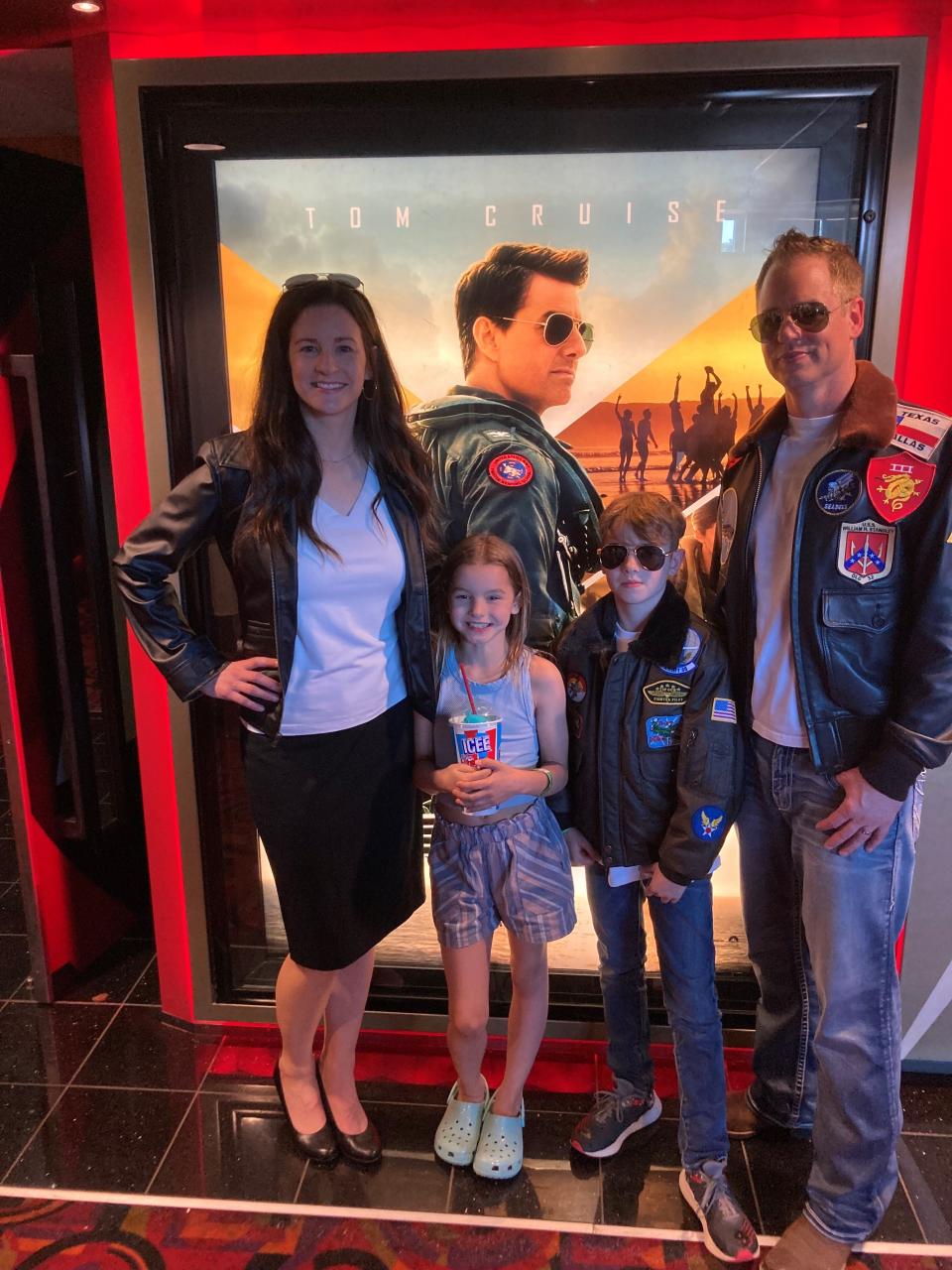 Chris Dickes (right) poses with his family members in front of a poster for "Top Gun: Maverick," where he appeared as an extra.