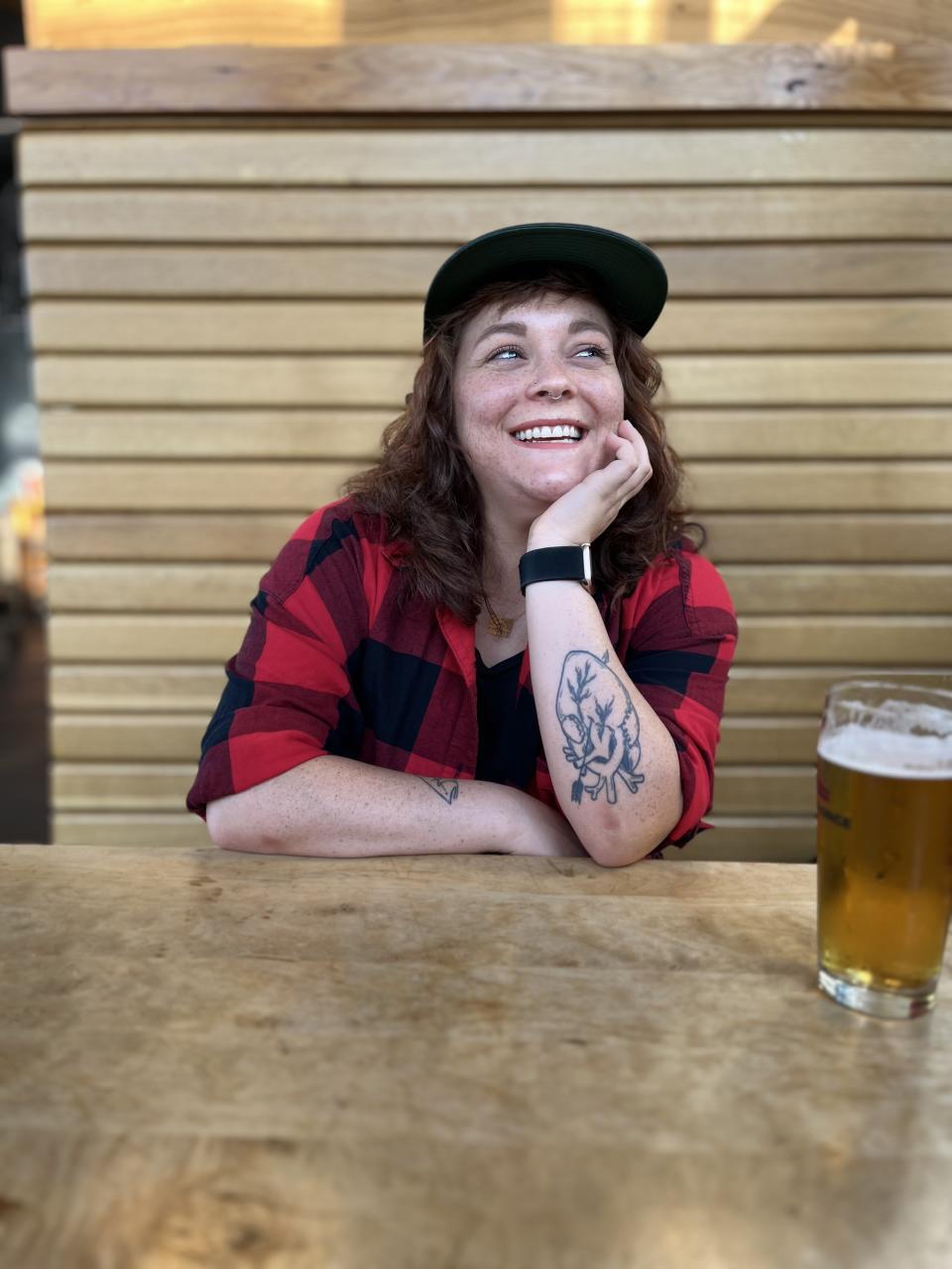 Hanna Brooks Olsen, smiling and resting her chin on one hand, sits at a restaurant table.