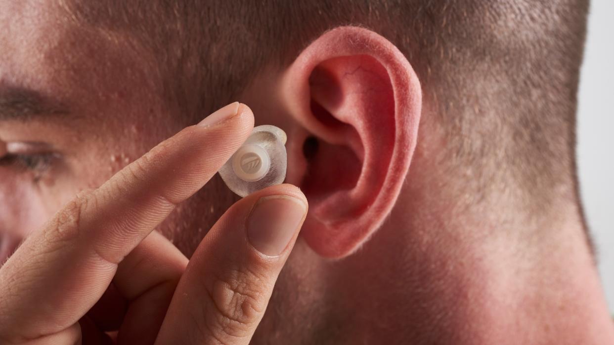  A man places an earplug into his ear. 