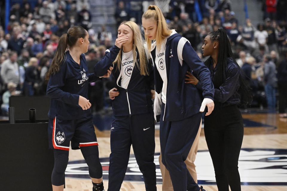 Connecticut's Nika Muhl, left, Paige Bueckers, center, and Dorka Juhasz, second from right, walk off the court during a medical emergency involving Associate Head Coach Chris Dailey before an NCAA basketball game against North Carolina State, Sunday, Nov. 20, 2022, in Hartford, Conn. (AP Photo/Jessica Hill)