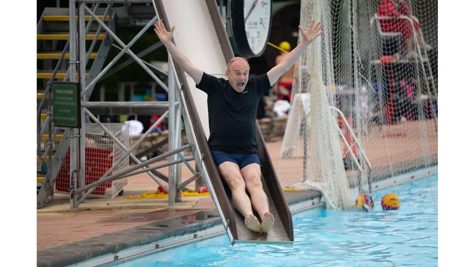 Ed Davey going down a slide into a swimming pool