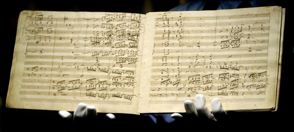 An opened book shows pages filled with musical notes.