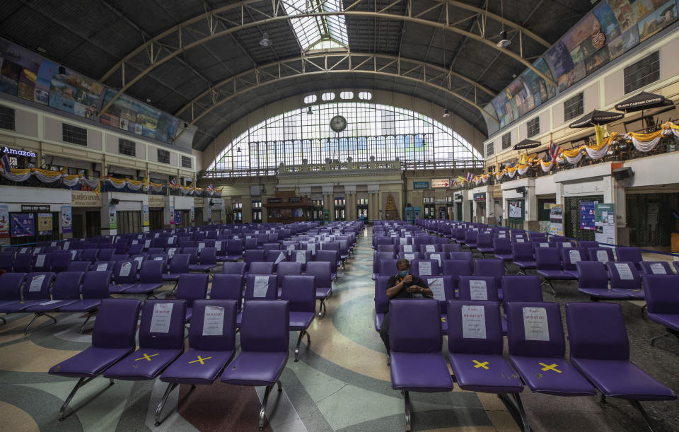 FILE- In this April 14, 2020, file photo, a lone passenger wearing a face mask help curb the spread the coronavirus sits in spread out seating at the Hua Lamphong Railway Station in Bangkok, Thailand. Shortages of power, computer chips and other parts, soaring shipping costs and shutdowns of factories to battle the pandemic are taking a toll on Asian economies. (AP Photo/Sakchai Lalit, File)