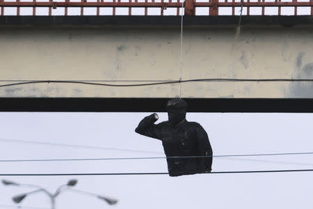 The remains of a statue of Venezuela's late President Hugo Chavez is seen hanging from a pedestrian bridge after it was destroyed in San Felix, Venezuela January 23, 2019. REUTERS/William Urdaneta