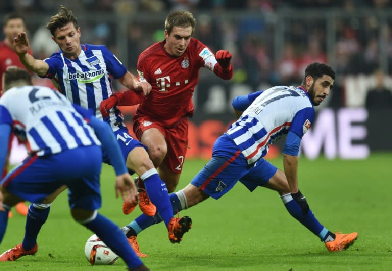 Bayern Munich's Philipp Lahm (C) is challenged by Hertha Berlin's Valentin Stocker (L) and Tolga Cigerci during their Bundesliga match in Munich on November 28, 2015