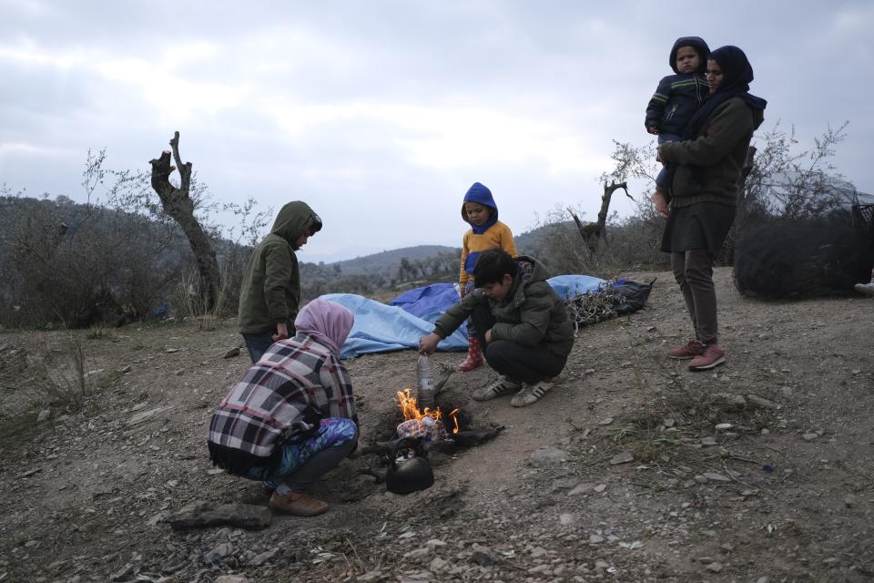 Migrants warm themselves outside the Moria refugee camp on the northeastern Aegean island of Lesbos, Greece, on Tuesday, Jan. 21, 2020. Some businesses and public services on the eastern Aegean island are holding a 24-hour strike on Wednesday to protest the migration situation, with thousands of migrants and refugees are stranded in overcrowded camps in increasingly precarious conditions. (AP Photo/Aggelos Barai)