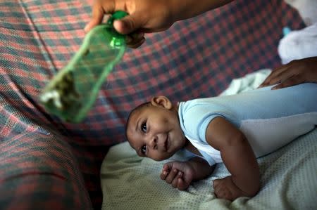Jackeline, 26, uses a green bottle to stimulate to her son Daniel who is four months old, inside of their house in Olinda, near Recife, Brazil, February 11, 2016. REUTERS/Nacho Doce