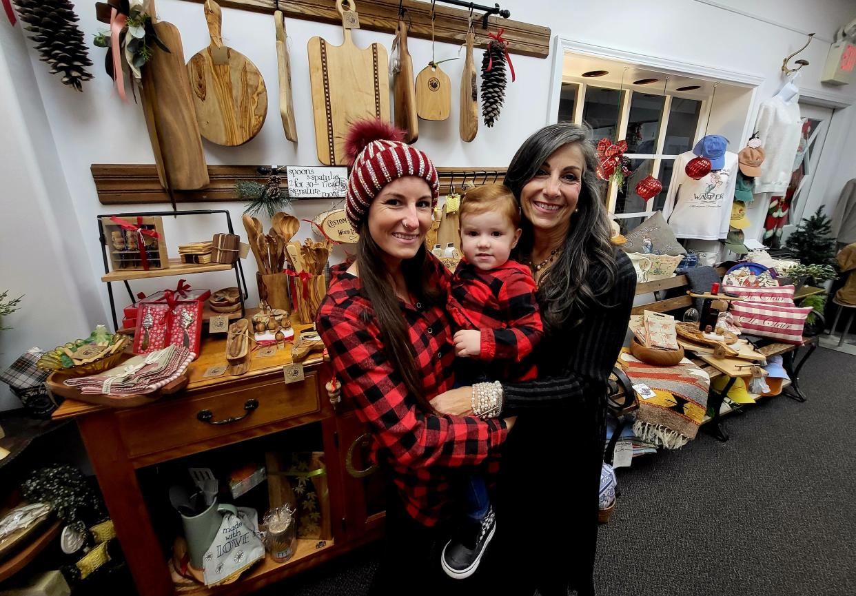 Daughter and mother Caitlin and Patti Barnum, owners of the Bear and the Hare, stand in their store on Friday, Nov. 17, 2023, at Riverview Plaza in St. Clair, holding Caitlin's daughter. They're among roughly a dozen retailers at the downtown mall, bracing for the holiday shopping season.