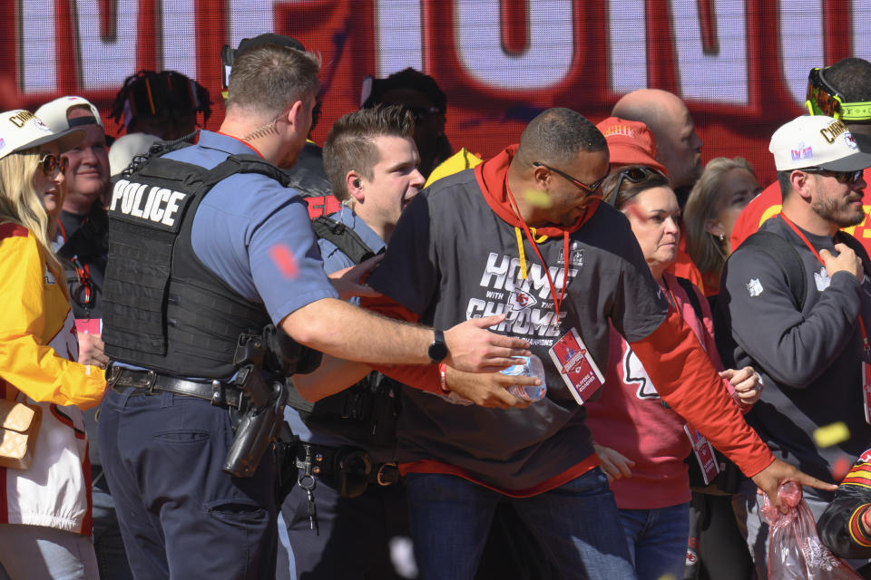 Police clear the Kansas City Chiefs from the stage after a shooting at their Super Bowl victory rally in Kansas City, Mo., Wednesday, Feb. 14, 2024. Authorities in Kansas City are trying to decipher who was behind the mass shooting that unfolded Wednesday. (AP Photo/Reed Hoffmann)