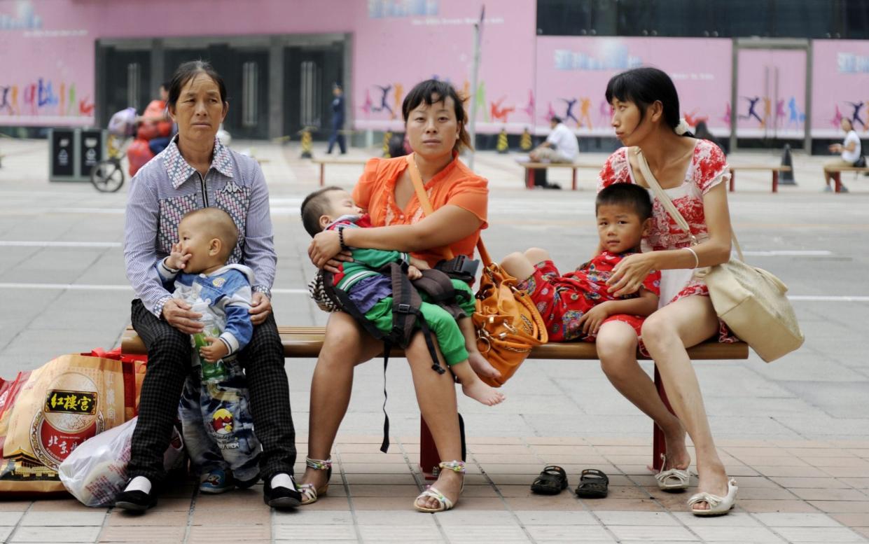 Chinese women with their babies as they sit on a bench along a street in Beijing - AFP