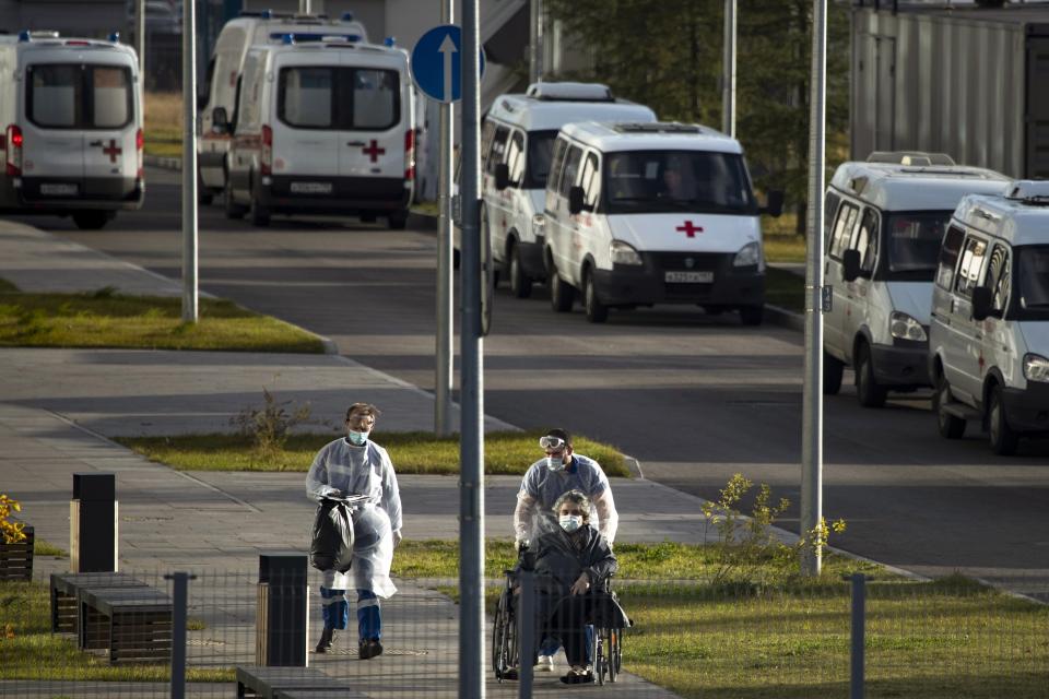 A medical worker wearing protective gear push a wheelchair with a patient suspected of having coronavirus at a hospital outside Moscow, Russia, Thursday, Oct. 15, 2020. Life outside hospitals remains largely normal. Moscow officials recommended the elderly and those who have chronic illnesses stay home. They ordered employers to make 30% of their staff work from home, extended school vacation by a week and moved middle and high school students to online classes. (AP Photo/Pavel Golovkin)