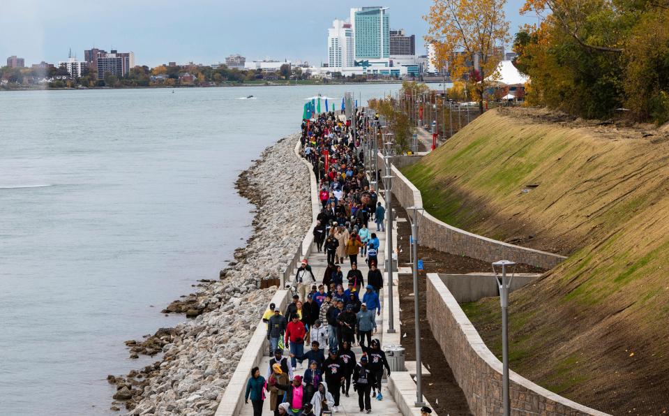 Dozens of pedestrians walk during the Uniroyal Promenade ribbon-cutting ceremony on Detroit’s Riverwalk in Detroit on Saturday, Oct. 21, 2023. The new Uniroyal Promenade completes the 3.5 mile-long Riverwalk and provides access to Belle Isle.