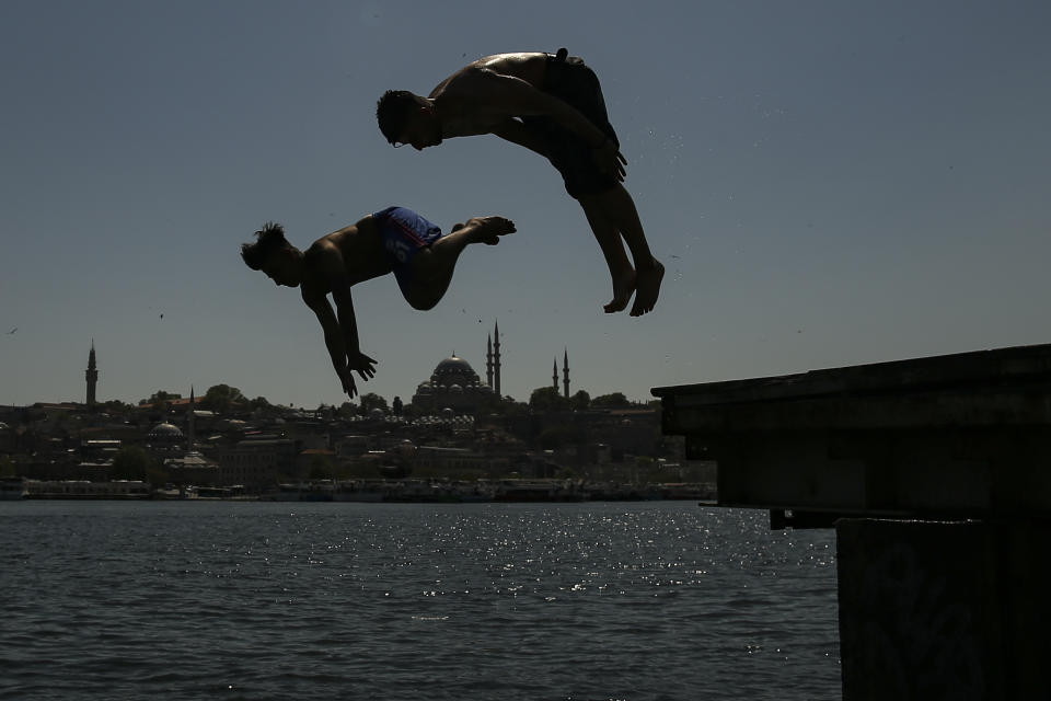 Backdropped by the historical Suleymaniye mosque youths jump from the Galata Bridge into the Golden Horn leading to the Bosphorus Strait separating Europe and Asia, in Istanbul, Friday, May 14, 2021. Turkey is in the final days of a full coronavirus lockdown and the government has ordered people to stay home and businesses to close amid a huge surge in new daily infections. But millions of workers are exempt and so are foreign tourists. Turkey is courting international tourists during an economic downturn and needs the foreign currencies that tourism brings to help the economy as the Turkish lira continues to sink. (AP Photo/Emrah Gurel)