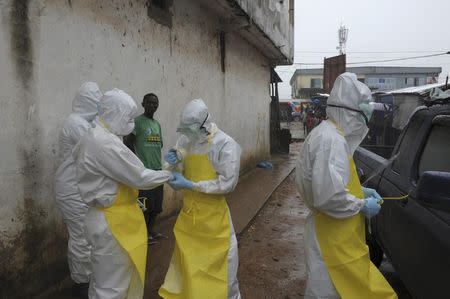 Health workers wearing protective clothing prepare before carrying an abandoned dead body presenting with Ebola symptoms at Duwala market in Monrovia August 17 2014. REUTERS/2Tango