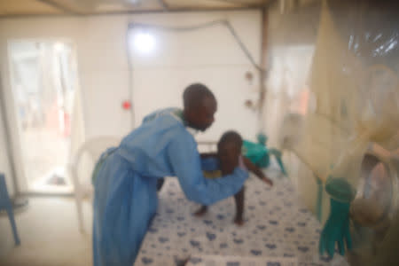 An infant Ebola patient is tended to by an Ebola survivor inside the Biosecure Emergency Care Unit (CUBE) at the ALIMA (The Alliance for International Medical Action) Ebola treatment centre in Beni, Democratic Republic of Congo, March 31, 2019. Picture taken March 31, 2019. Picture taken through a plastic divider. REUTERS/Baz Ratner