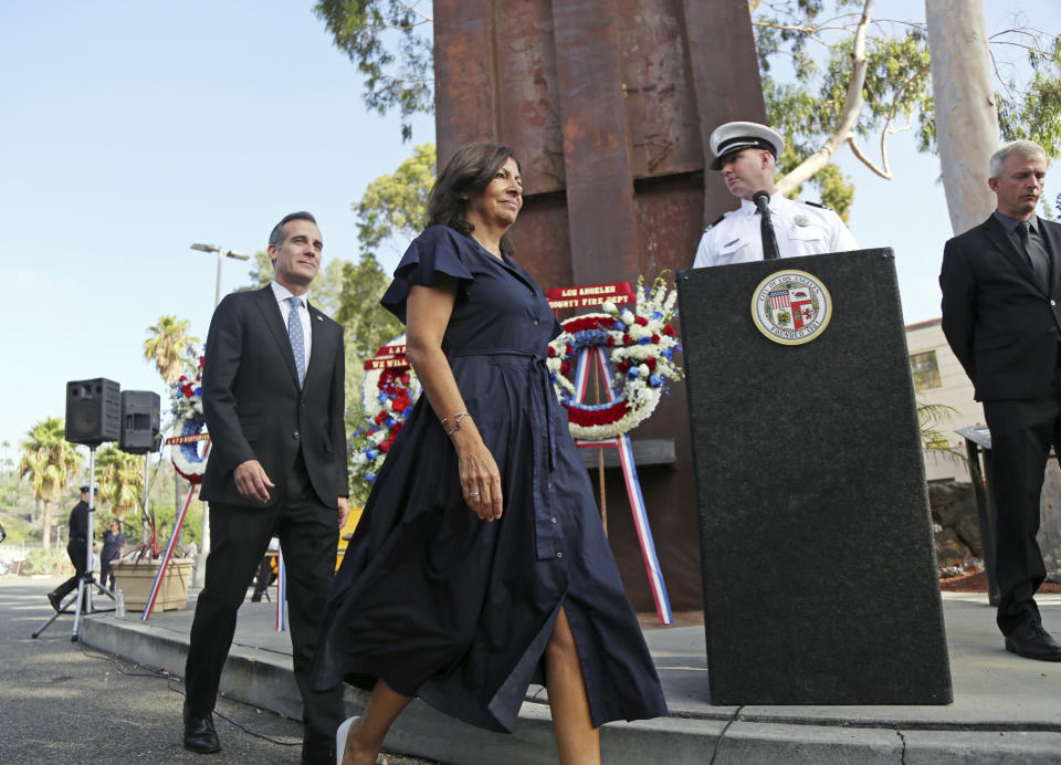 Los Angeles Mayor Eric Garcetti and Paris Mayor Anne Hidalgo participate in a ceremony marking the 17th anniversary of the Sept. 11, 2001 terrorist attacks on America, at the Los Angeles Fire Department's training center Tuesday, Sept. 11, 2018. In the background is the largest fragment of the World Trade Center outside New York. The mayors of Paris and Los Angeles met Tuesday ahead of a global climate summit to memorialize the victims of the 9/11 attacks on the U.S,. and to talk about the commonalities between the two cities amid an increasingly divided world. They then helped pack lunches for the needy. (AP Photo/Reed Saxon)