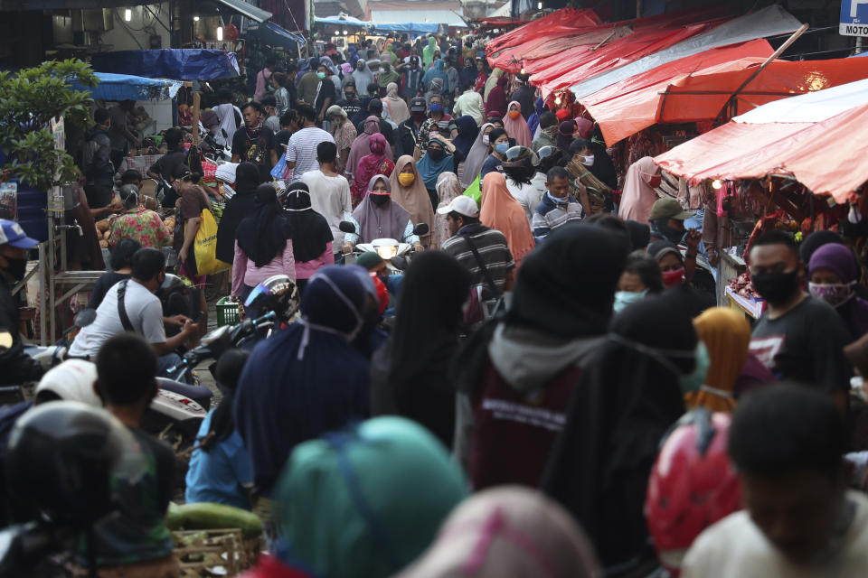 People shop in preparation of the upcoming Eid al-Fitr holiday that marks the end of the holy fasting month of Ramadan amid fears of the new coronavirus outbreak at a market in Jakarta, Indonesia, Friday, May 22, 2020. (AP Photo/Achmad Ibrahim)